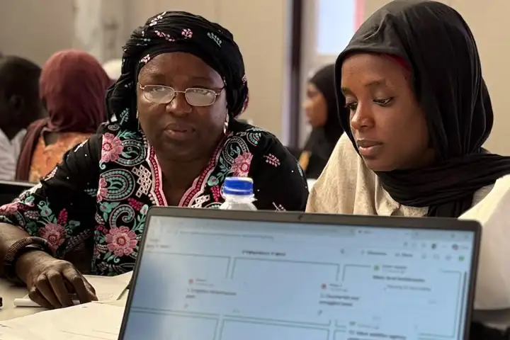 Two participants follow a group exercise on a laptop at a workshop