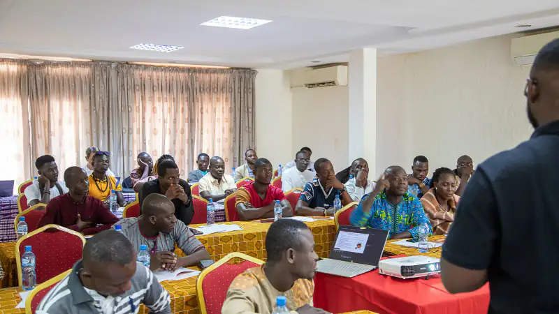 A Sense trainer presents to a room of business owners at a workshop, Burkina Faso