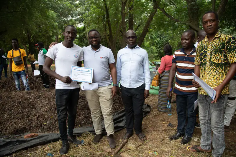 Young people holding certificates at a compost training site