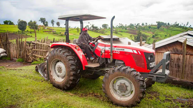 A farmer driving a red tractor on a hillside farm