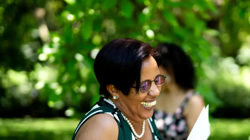 A smiling participant holding her certificate at an outdoor ceremony