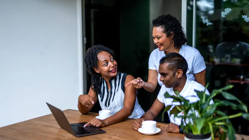 Three Sense colleagues talking over a laptop and coffee