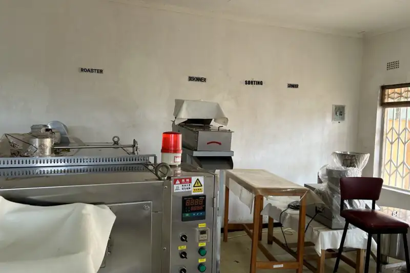 A small processing room with a roaster, deskinner, sorting table and grinder, Malawi