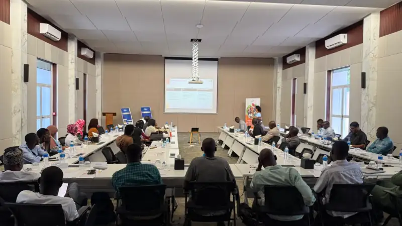 Participants at long tables listen to a presentation in a workshop room, Burkina Faso