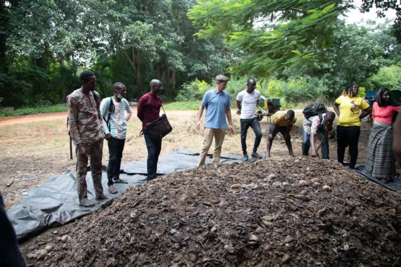 Trainees and a Sense consultant gather round a compost heap