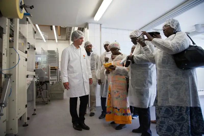 Visitors in hairnets and white coats on a guided tour of a food factory